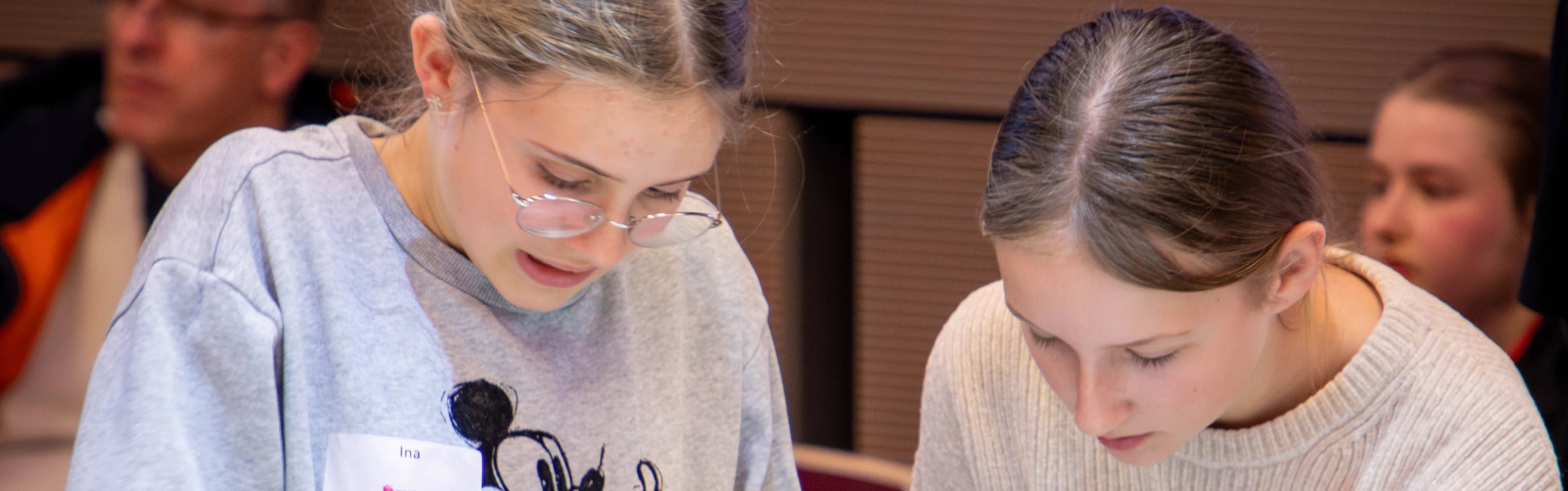 Zwei Mädchen arbeiten zusammen an einem Bauprojekt mit farbigen Bausteinen auf einem Tisch.