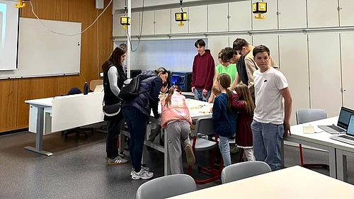 Eine Gruppe von Kindern und Jugendlichen arbeitet gemeinsam an einem Tisch in einem Raum.