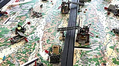 Eine LEGO-Szene mit verschiedenen Bauwerken auf einer Landschaftsoberfläche, die einen Fluss und Berge zeigt.