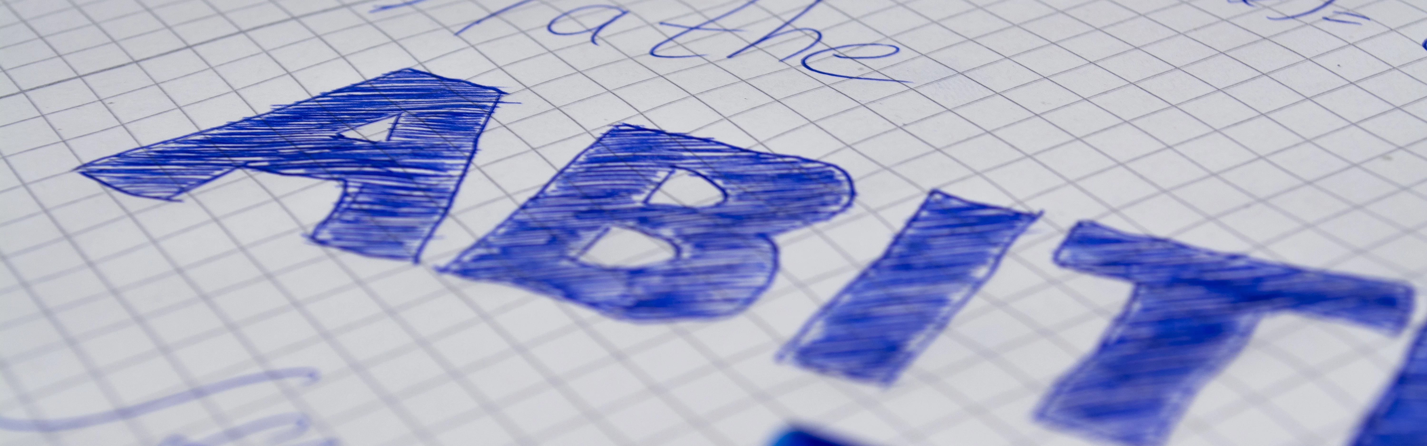 Auf einem karierten Blatt Papier steht "Mathe ABITUR" in blauer Schrift, daneben ein blauer Stift.
