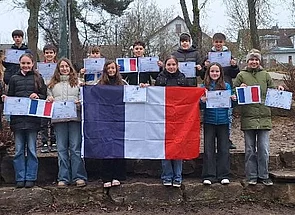 Eine Gruppe von Jugendlichen hält eine französische Flagge und Urkunden in die Kamera.
